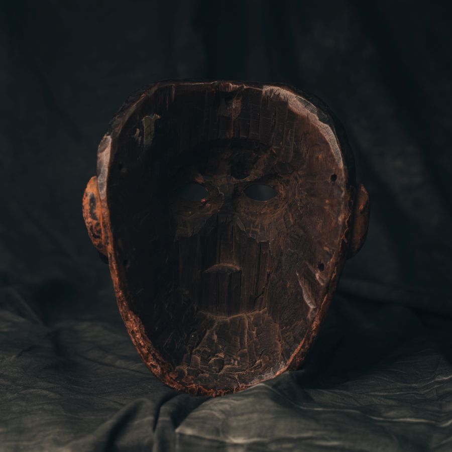 Antique 18th Century Guatemalan wood mask on a textured dark background