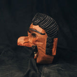 Side view of a wooden 18th Century Guatemalan mask with intricate carvings on a dark background
