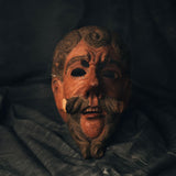 Traditional wood mask with intricate designs on a dark background