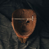 Hand painted wooden mask with string on a dark fabric background