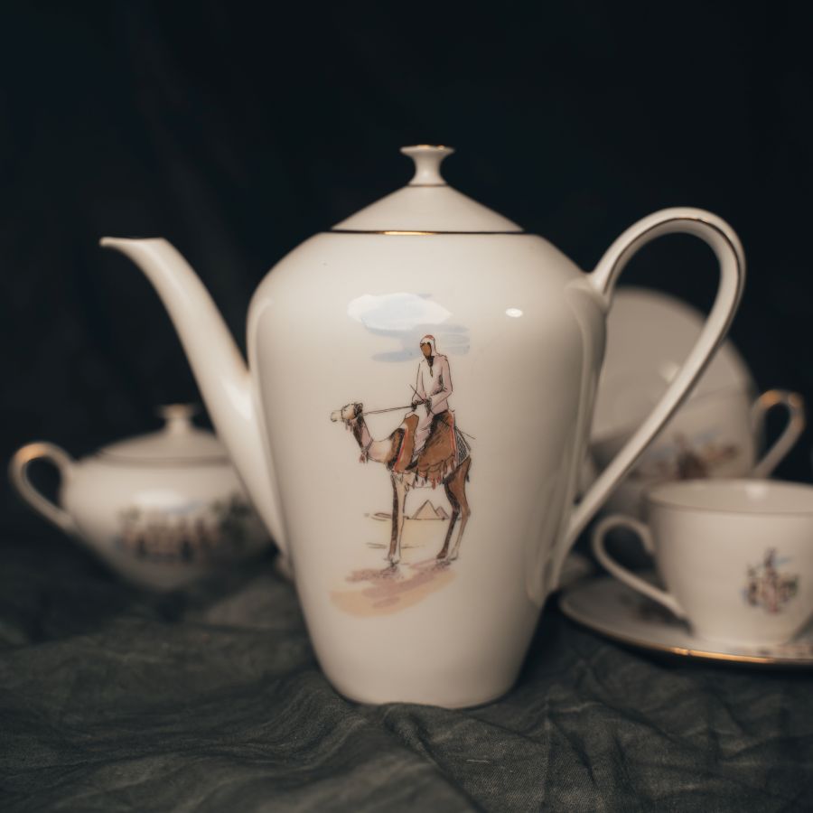 Tea set with a teapot featuring a camel rider design on a dark background