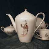 Tea set with a teapot featuring a camel rider design on a dark background