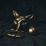Front view of a vintage brass fox-shaped door knocker with a sculpted face and long ears, styled against a dark background.