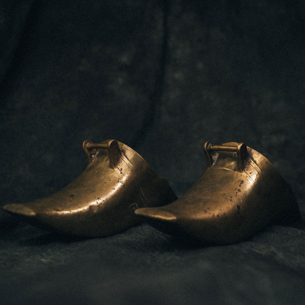 Full view of vintage brass Conquistador stirrups with curved frames and worn patina, styled as sculptural objects for home decor.
