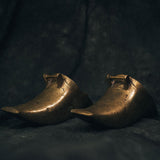 Full view of vintage brass Conquistador stirrups with curved frames and worn patina, styled as sculptural objects for home decor.