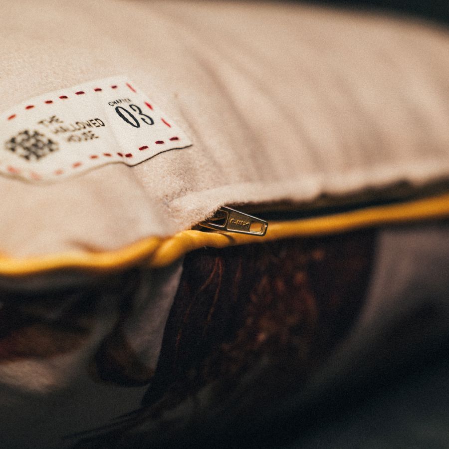 Close-up of the Elixir of Life pillow’s bottom zipper with gold piping, highlighting its refined finish and hidden closure.