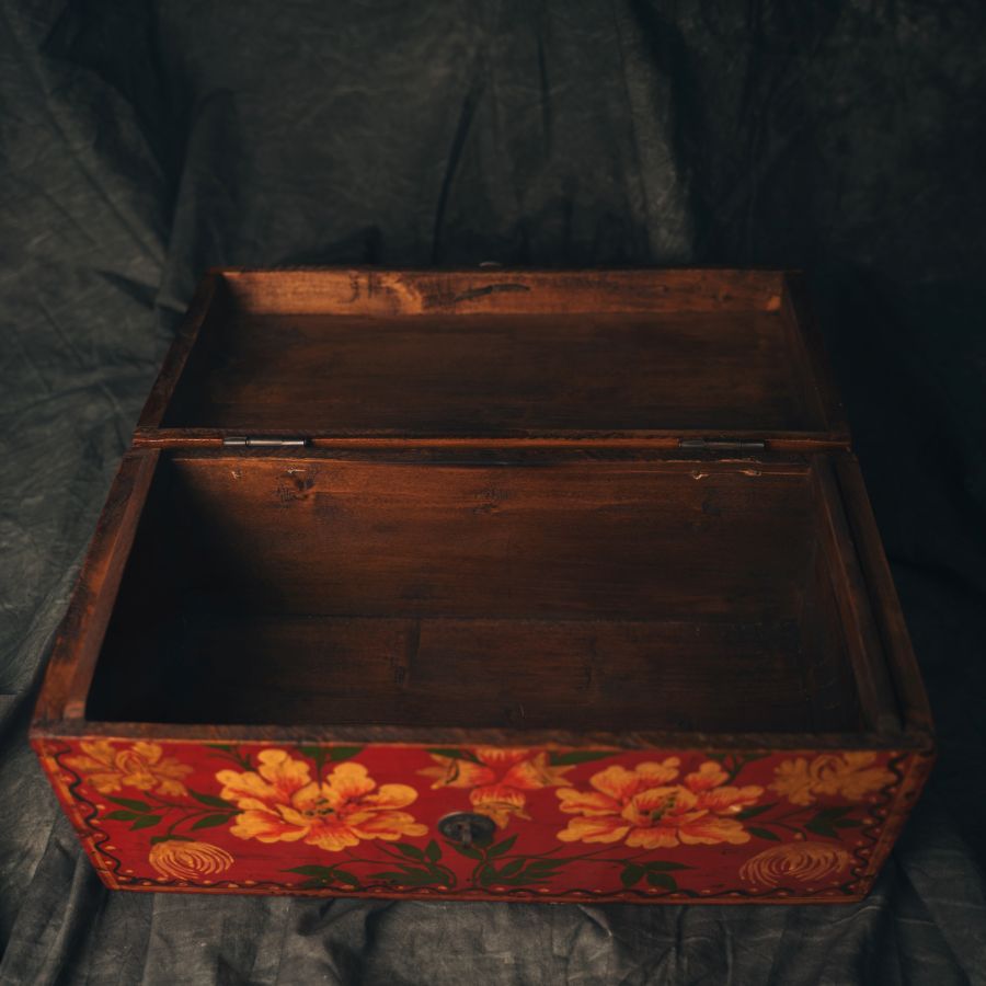 A photo of a open red Chinese wooden box with floral patterns