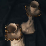 Two ornate aquarius Ivory candle holders with candles on a dark background