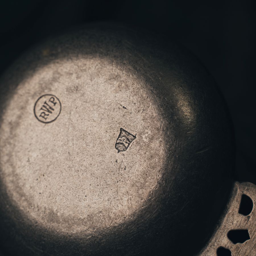 Close-up photo of the bottom of the pewter bowl with branding and design details.