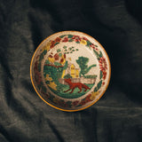 Decorative plate with a colorful design on a dark fabric background