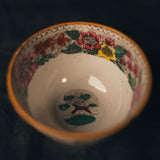 Ceramic bowl with floral rim and colorful design on a dark background