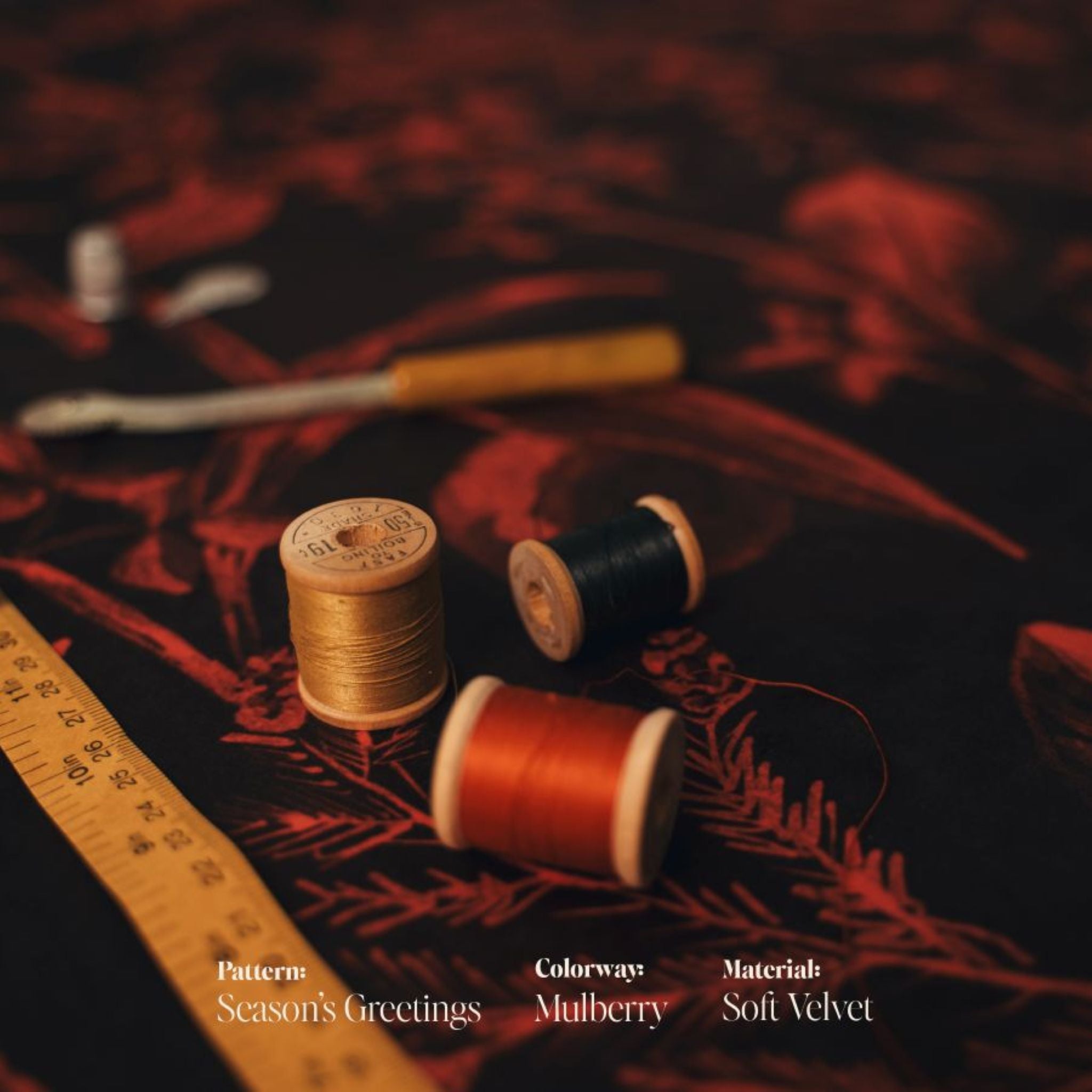 Spools of thread and a ruler on the Seasons Greetings mulberry velvet fabric with 'Season's Greetings' text overlay.