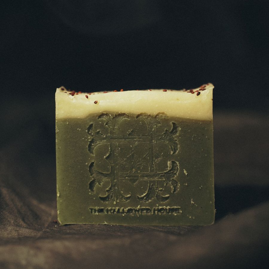 Unwrapped Season's Greetings soap resting on a clean surface, showcasing its  texture and festive embossing.