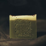 Unwrapped Season's Greetings soap resting on a clean surface, showcasing its  texture and festive embossing.