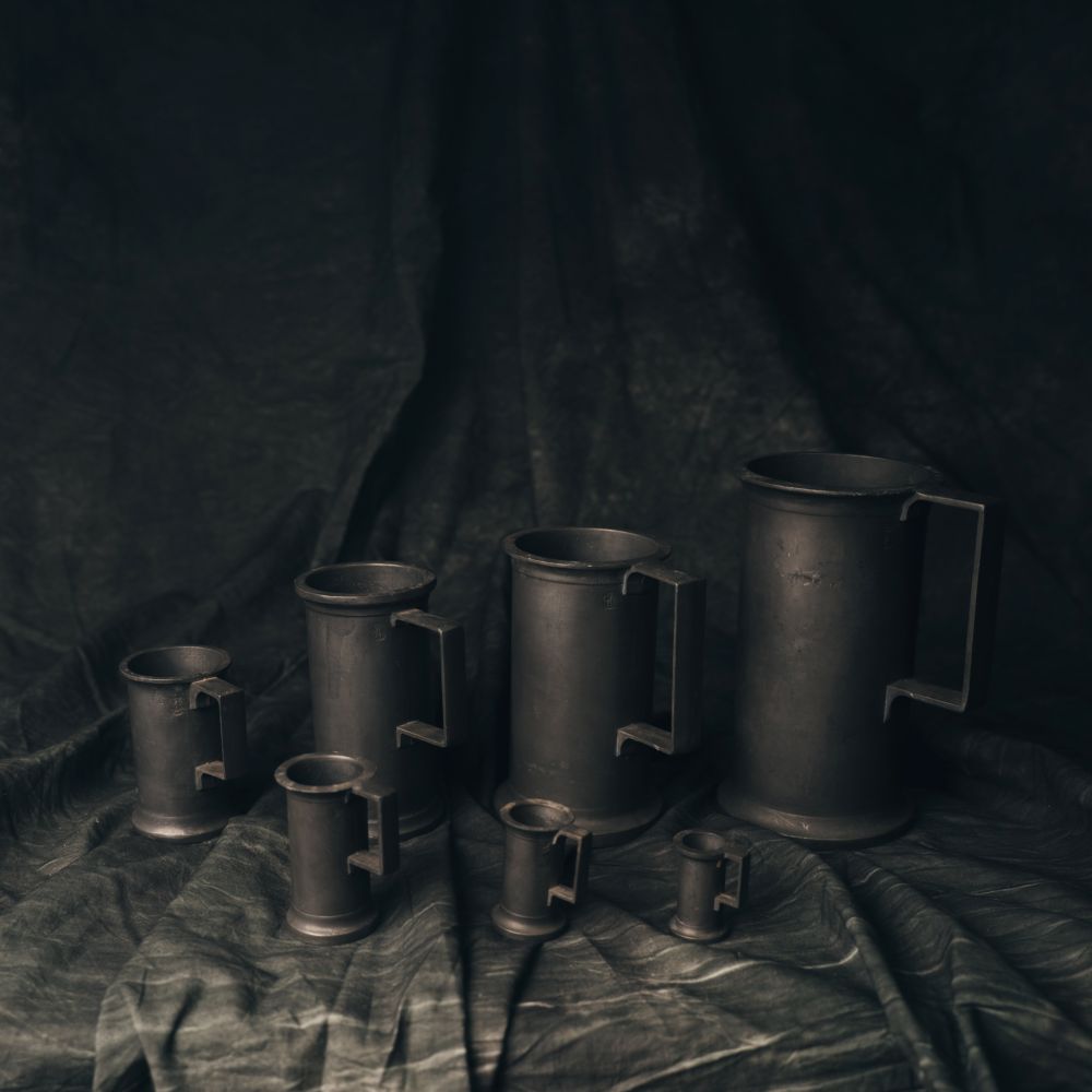 Set of Pewter Measuring Cups on a dark fabric background