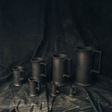 Set of Pewter Measuring Cups on a dark fabric background