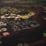 Close-up of a cross-stitched piece with floral patterns of the The Night's Tale Amethyst Fabric 