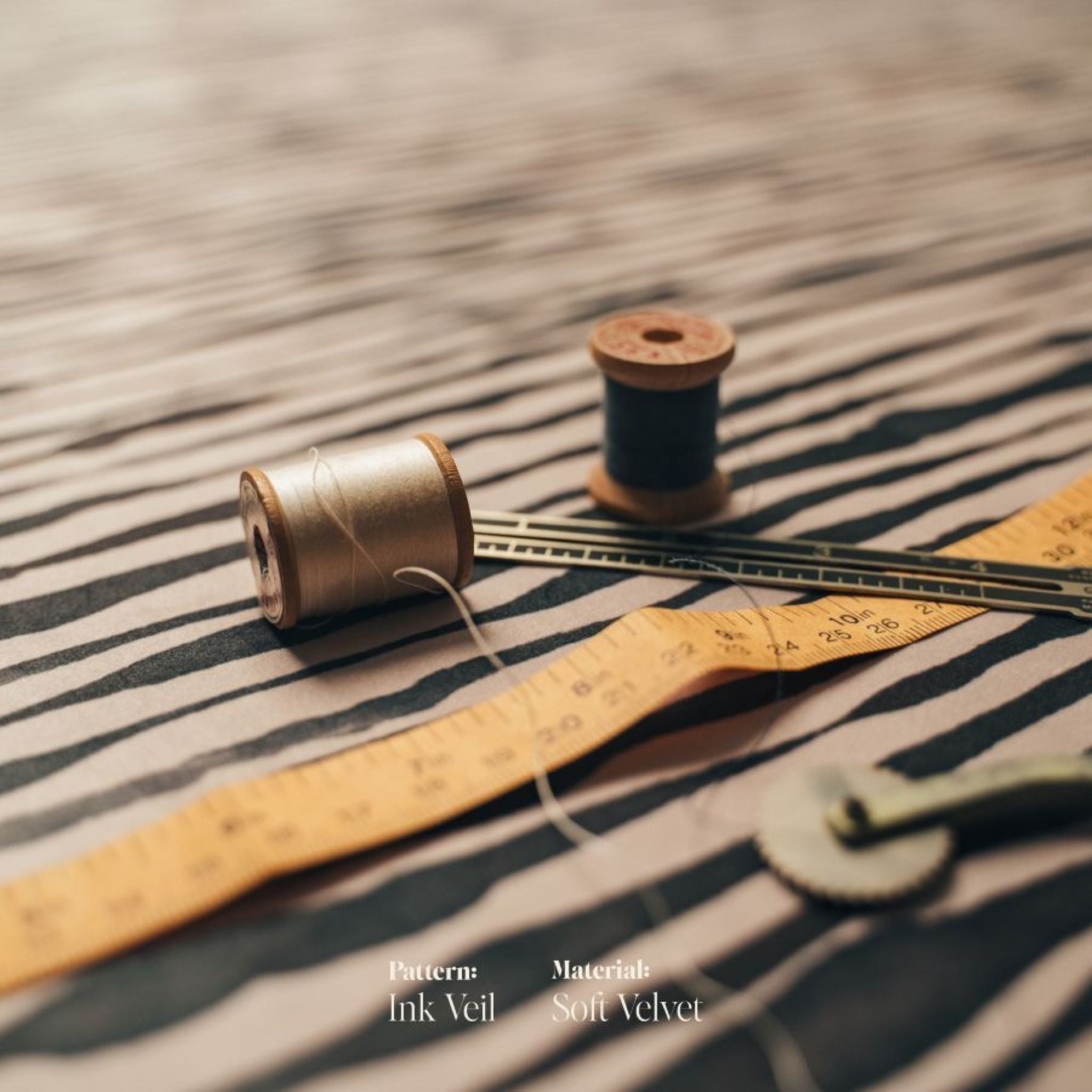 Spools of thread and a measuring tape on the black and white striped Night's Tale Ink Veil Velvet Fabric