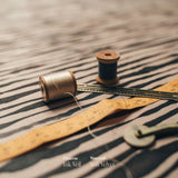 Spools of thread and a measuring tape on the black and white striped Night's Tale Ink Veil Velvet Fabric
