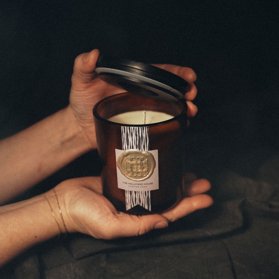 Hands holding The Night's Tale candle, showing its scale and moody label inspired by midnight storytelling.