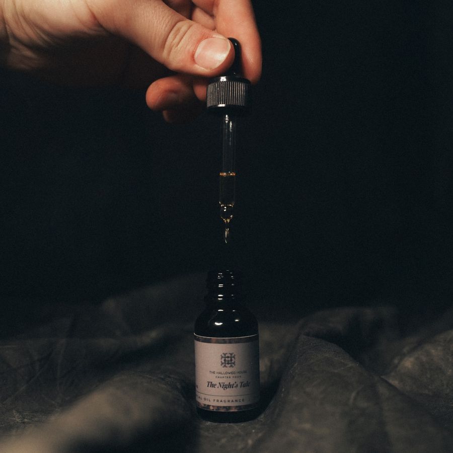 Close-up of The Night's Tale oil dropper above the bottle, revealing the dark, rich blend with notes of ink and woods.