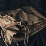 Close-up of a folded fabric item with a drawstring on a dark background