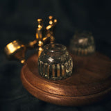 Close-up of a dual glass inkwell in the open position with a wooden base on a dark background